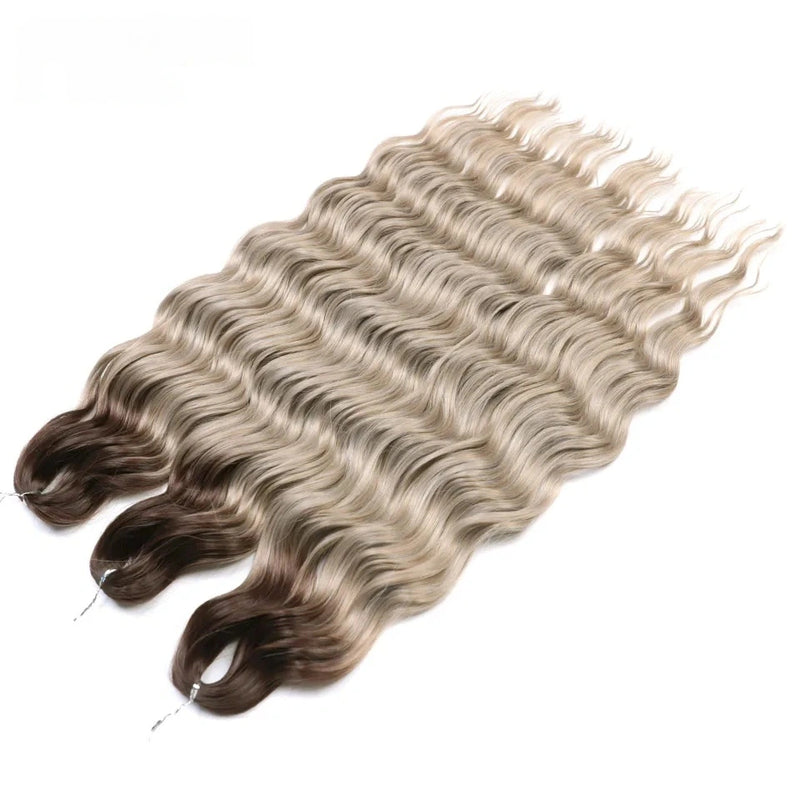 Three bundles of wavy hair extensions with a gradient from brown to blonde on a white background.